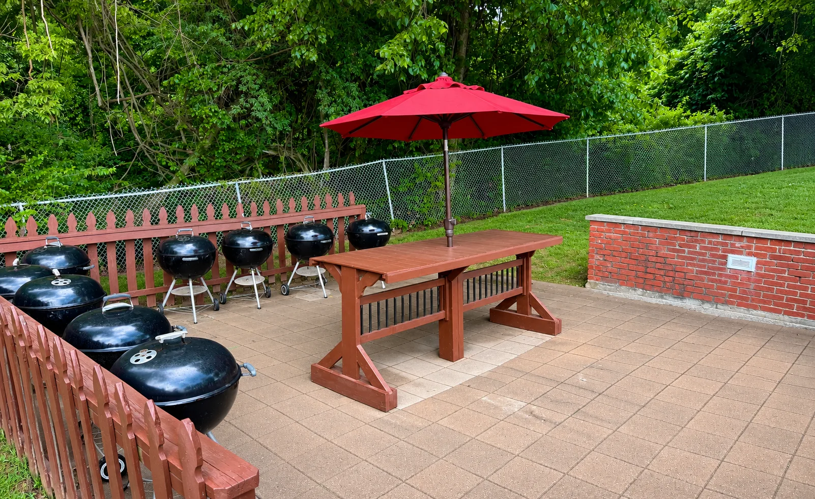 Outdoor charcoal grills and picnic table beneath a red umbrella